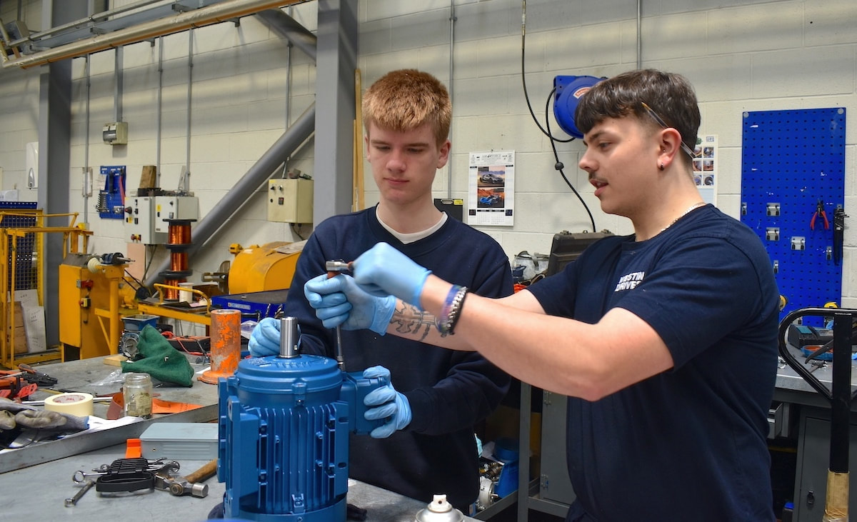 An apprentice shows a work experience student the workings of an electric motor
